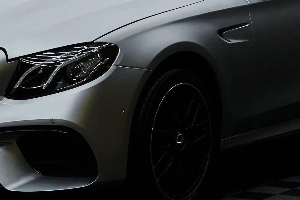 Чёрное кованое колесо седана Mercedes-AMG крупным планом, за ним модульный пол в клетку