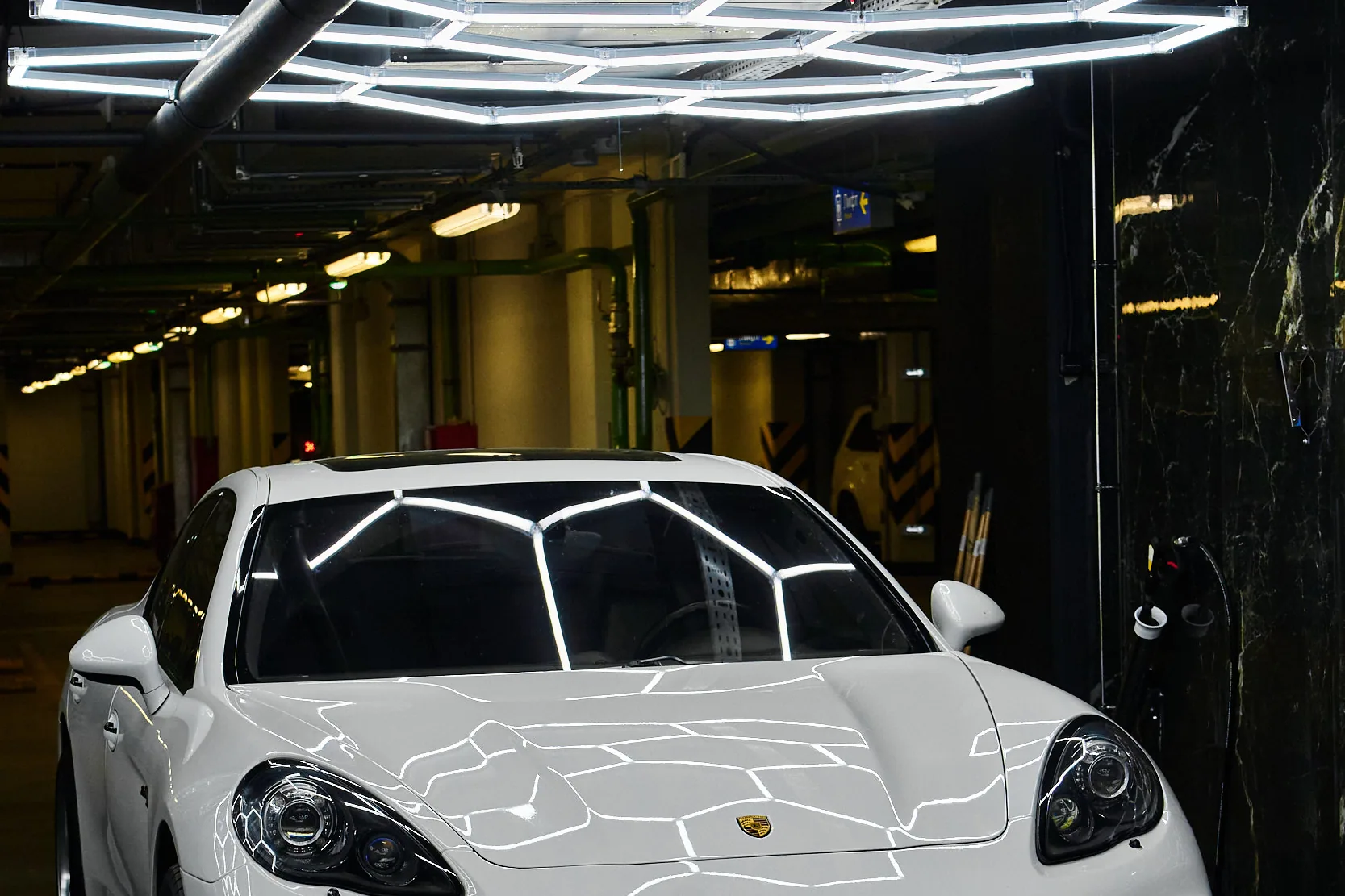 Белый Porsche Panamera анфас, световые соты отражаются в капоте и лобовом стекле