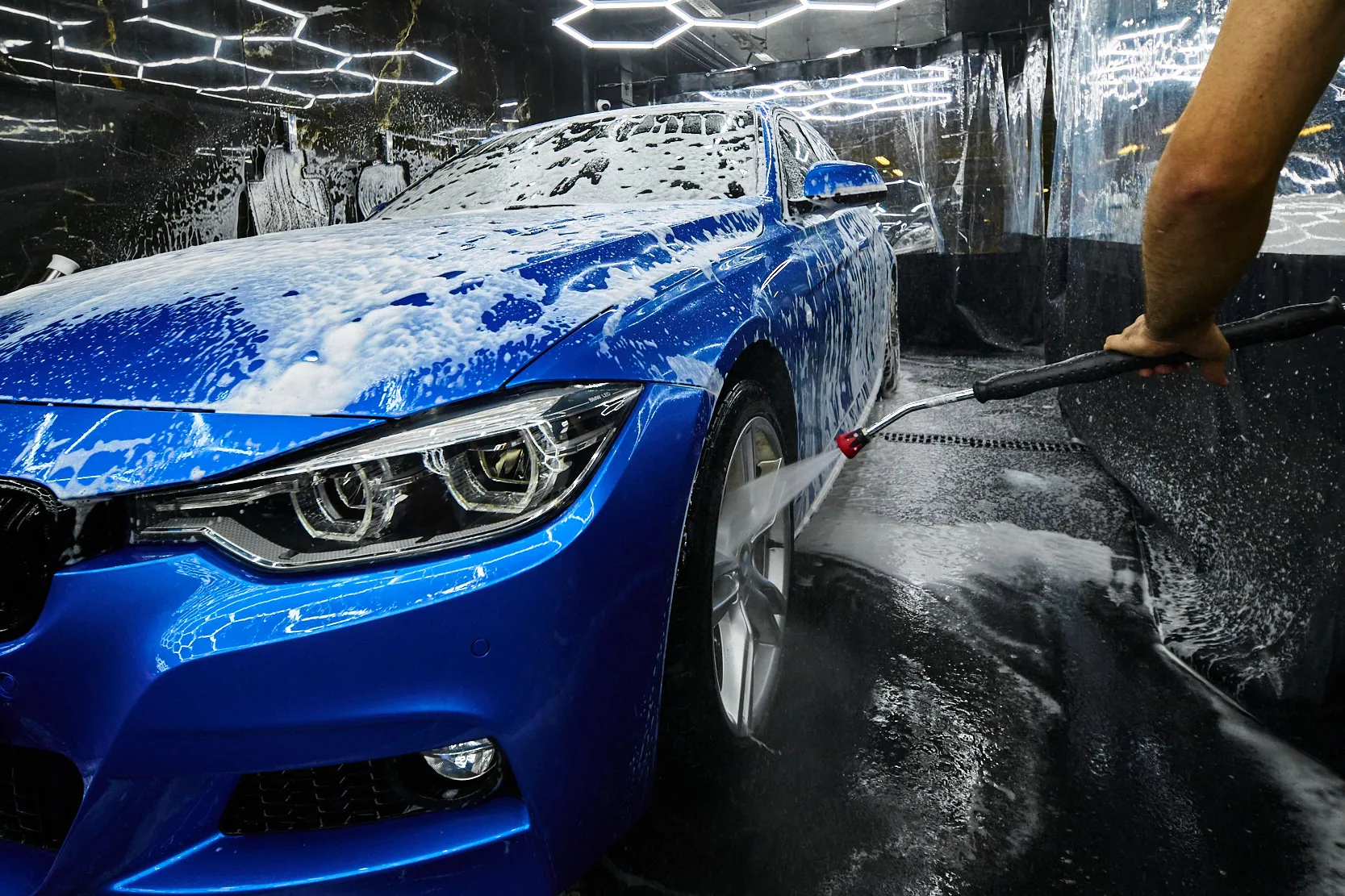 Смыв пены с колеса синего седана BMW аппаратом высокого давления