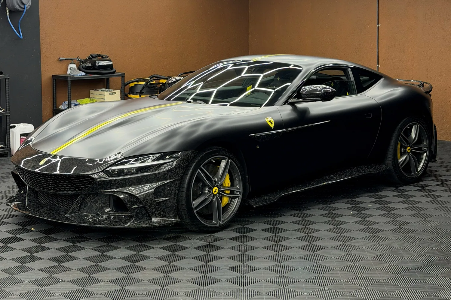 Тёмный Ferrari с жёлтой полосой на кузове в студии