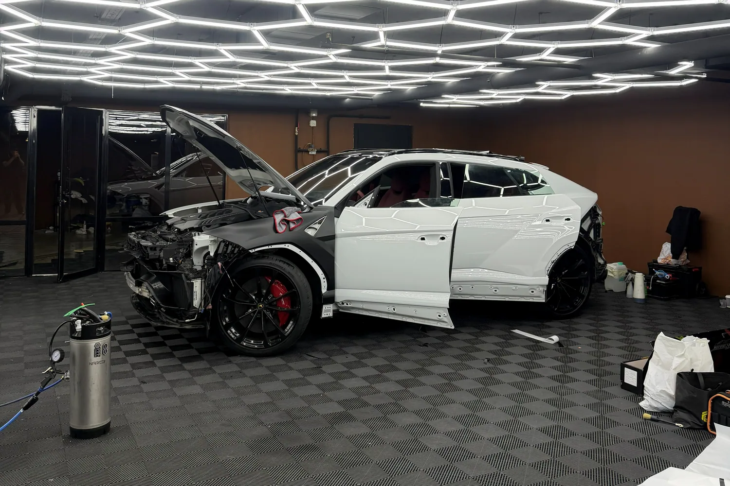 Белый Lamborghini Urus со снятыми наружными деталями в боксе